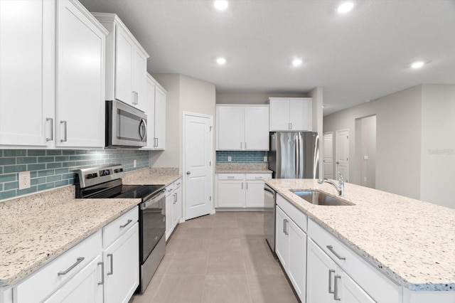 kitchen with stainless steel appliances, white cabinetry, and a kitchen island with sink