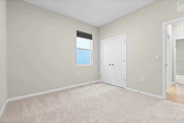 unfurnished bedroom featuring light carpet and a closet