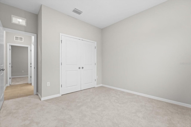 unfurnished bedroom with a closet and light carpet