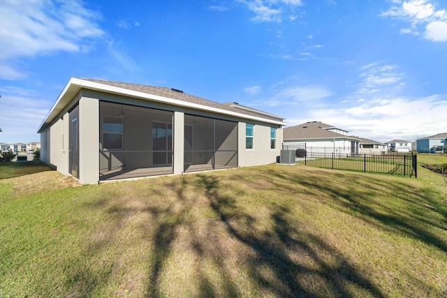 back of property with a sunroom, a lawn, and central air condition unit