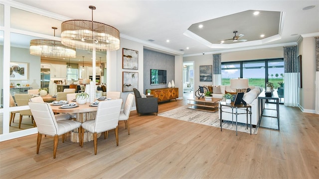 dining room featuring ceiling fan with notable chandelier, light hardwood / wood-style floors, crown molding, and a raised ceiling