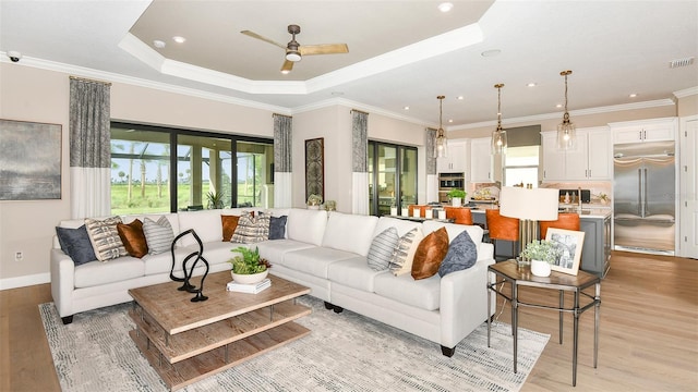 living room featuring ceiling fan, light hardwood / wood-style floors, a wealth of natural light, and a raised ceiling