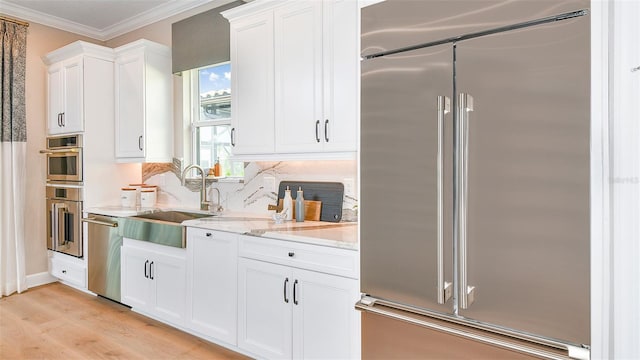 kitchen with white cabinetry, stainless steel appliances, light hardwood / wood-style floors, sink, and light stone counters