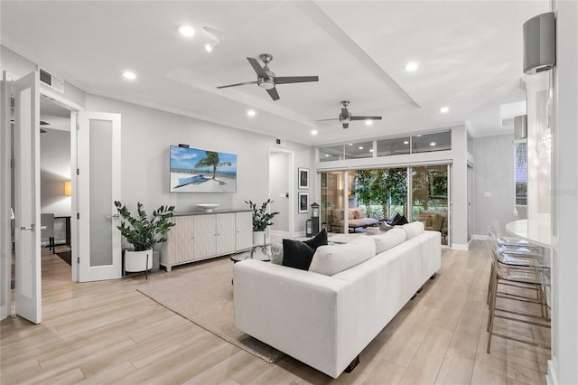 living room featuring light wood-type flooring, french doors, a raised ceiling, and ornamental molding