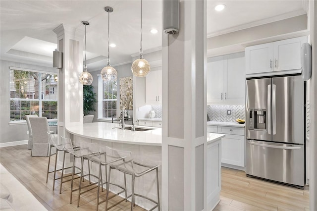 kitchen with pendant lighting, sink, white cabinets, stainless steel fridge with ice dispenser, and ornamental molding