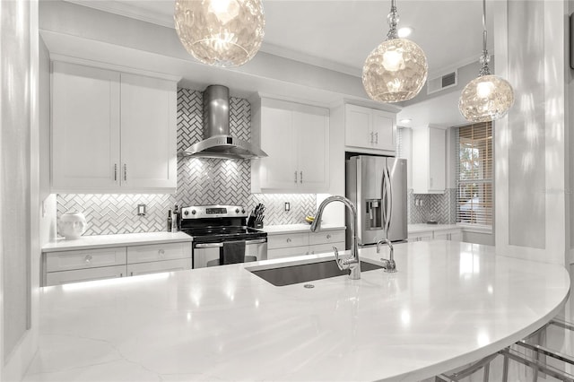 kitchen with appliances with stainless steel finishes, wall chimney range hood, white cabinets, sink, and backsplash