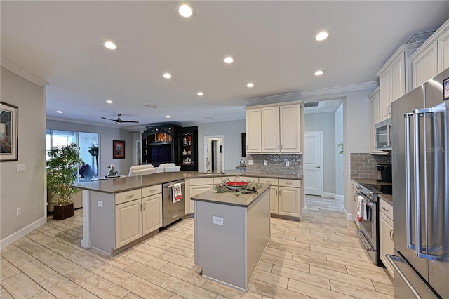 kitchen with kitchen peninsula, appliances with stainless steel finishes, decorative backsplash, and a center island