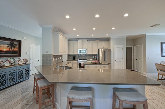 kitchen with a kitchen breakfast bar, sink, crown molding, and stainless steel appliances