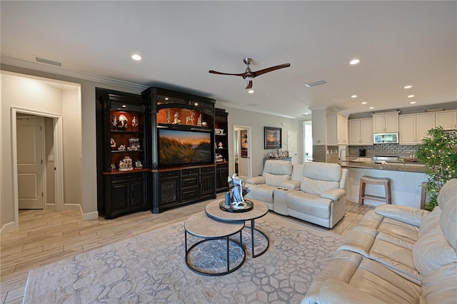 living room featuring ceiling fan, sink, and ornamental molding