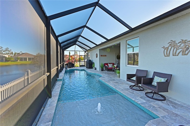 view of swimming pool with a water view, pool water feature, glass enclosure, and a patio area