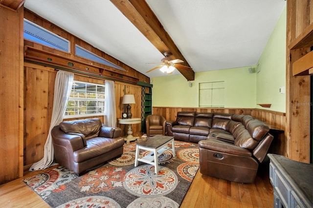 living room with hardwood / wood-style flooring, ceiling fan, wooden walls, and vaulted ceiling with beams