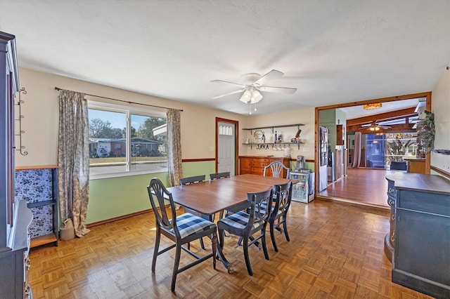 dining space with ceiling fan, dark parquet flooring, and a textured ceiling