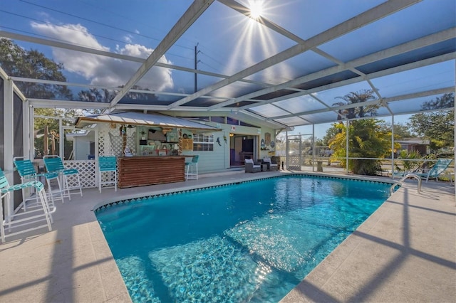 view of swimming pool featuring a bar, a patio area, and glass enclosure