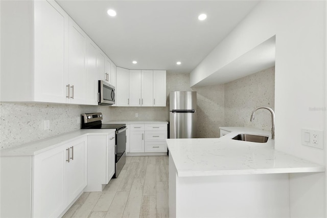 kitchen with stainless steel appliances, sink, decorative backsplash, and kitchen peninsula