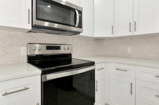 kitchen featuring white cabinets, light stone countertops, appliances with stainless steel finishes, and backsplash