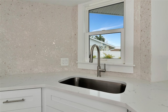 details with light stone countertops, sink, and white cabinets