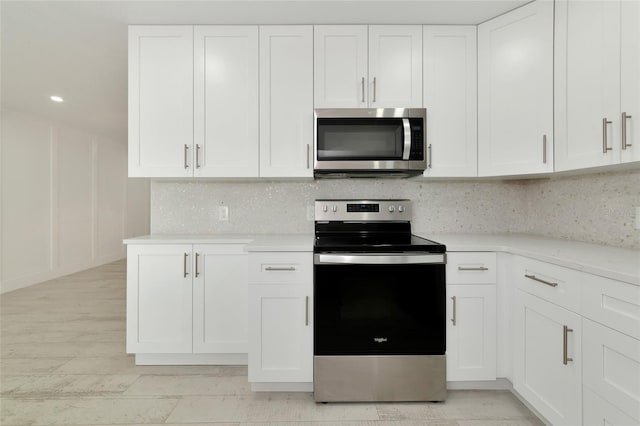 kitchen featuring white cabinets, light stone countertops, appliances with stainless steel finishes, and backsplash