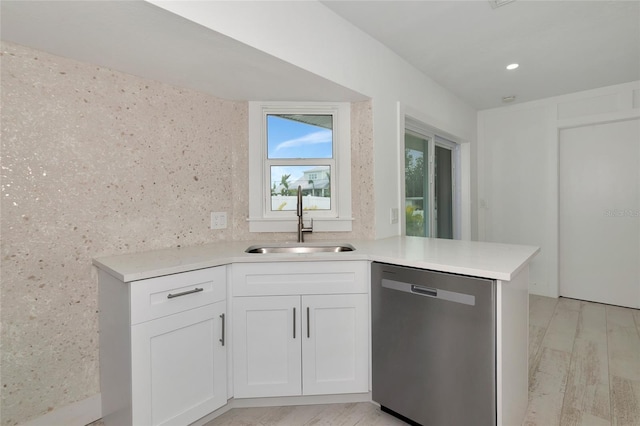 kitchen featuring white cabinetry, stainless steel dishwasher, kitchen peninsula, and sink