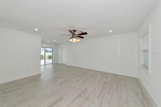 unfurnished room with ceiling fan, a textured ceiling, and light wood-type flooring