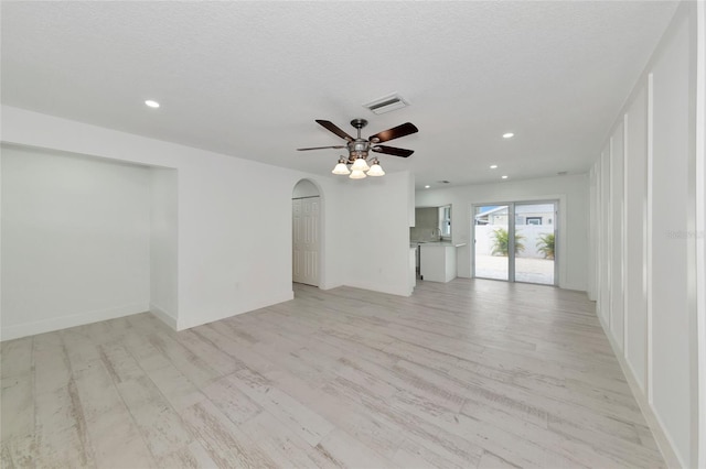 empty room featuring a textured ceiling, ceiling fan, and light wood-type flooring