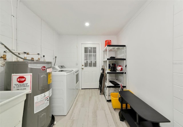 washroom featuring water heater, sink, independent washer and dryer, crown molding, and light wood-type flooring