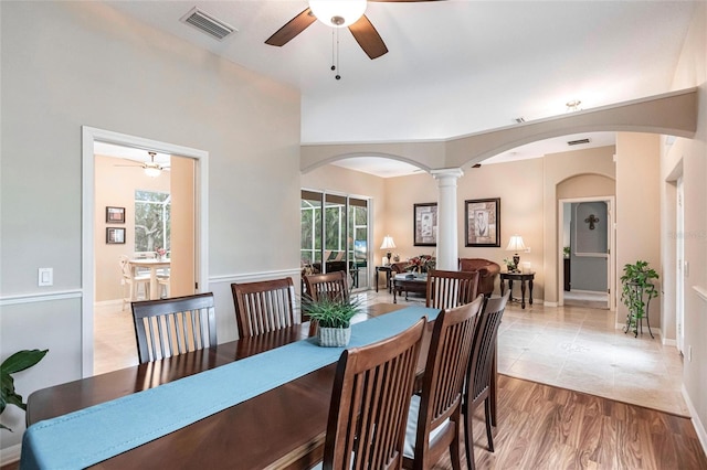 dining space featuring light wood-type flooring, ornate columns, and ceiling fan