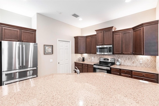 kitchen with appliances with stainless steel finishes, light stone countertops, and decorative backsplash