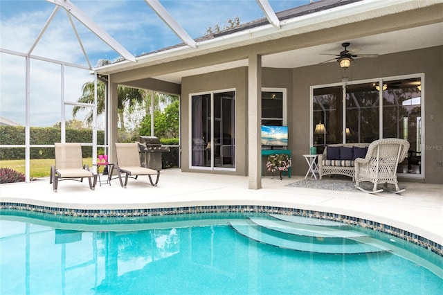 view of swimming pool with area for grilling, a patio area, glass enclosure, ceiling fan, and outdoor lounge area