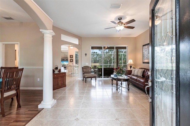 tiled living room with ceiling fan and ornate columns