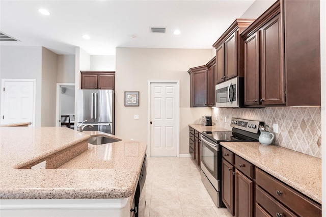 kitchen with appliances with stainless steel finishes, sink, backsplash, light tile patterned floors, and light stone countertops