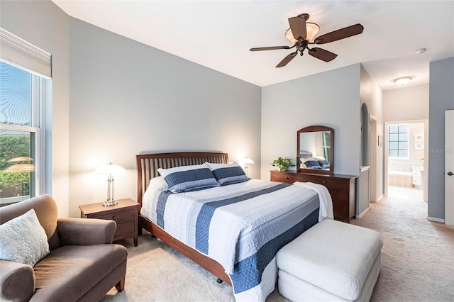 bedroom featuring multiple windows, light carpet, connected bathroom, and ceiling fan