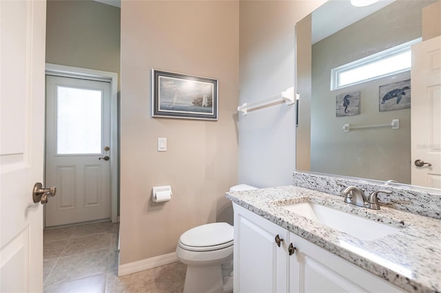 bathroom with toilet, vanity, and tile patterned flooring