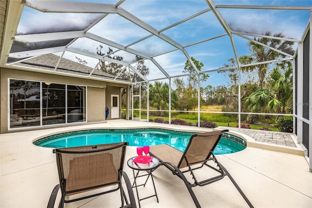 view of pool featuring glass enclosure and a patio area