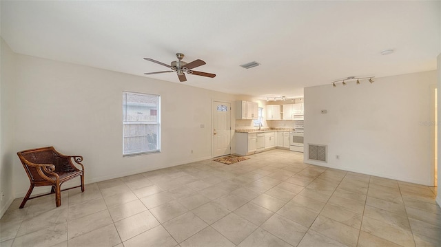 unfurnished living room with ceiling fan, sink, and light tile patterned floors