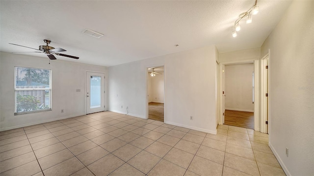 tiled empty room with a textured ceiling and ceiling fan