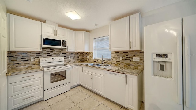 kitchen with light tile patterned floors, decorative backsplash, white appliances, white cabinets, and sink