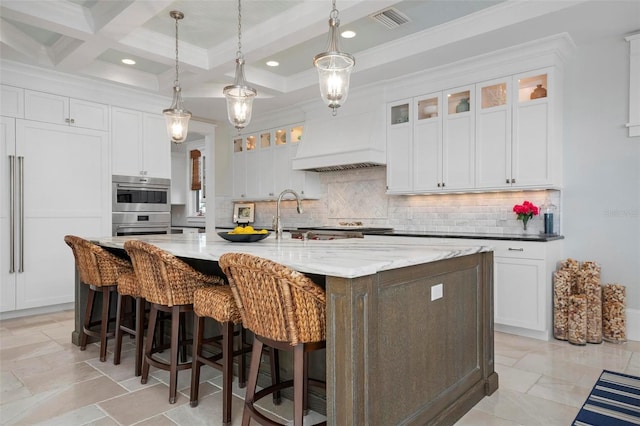 kitchen featuring visible vents, beamed ceiling, tasteful backsplash, white cabinets, and custom exhaust hood