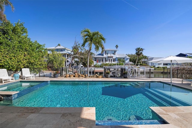 view of pool featuring a patio area, a residential view, a pool with connected hot tub, and fence