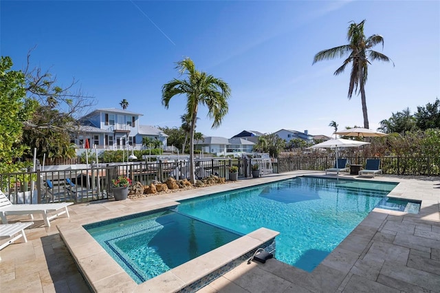 view of swimming pool featuring a residential view, a pool with connected hot tub, a patio, and fence