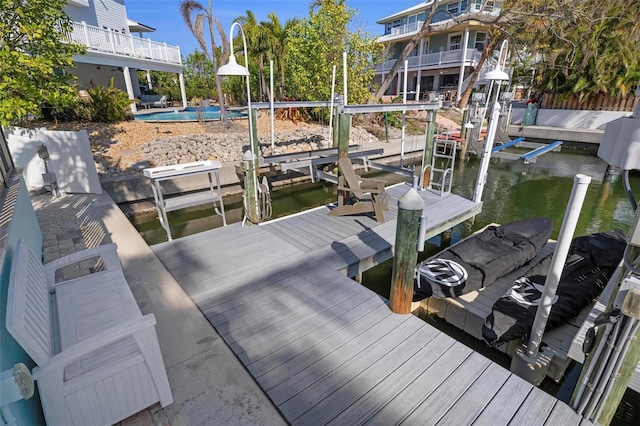 dock area with a fenced in pool, a water view, and boat lift