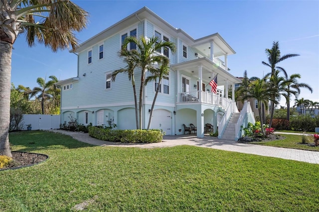 view of property exterior with fence, stairway, a lawn, covered porch, and decorative driveway