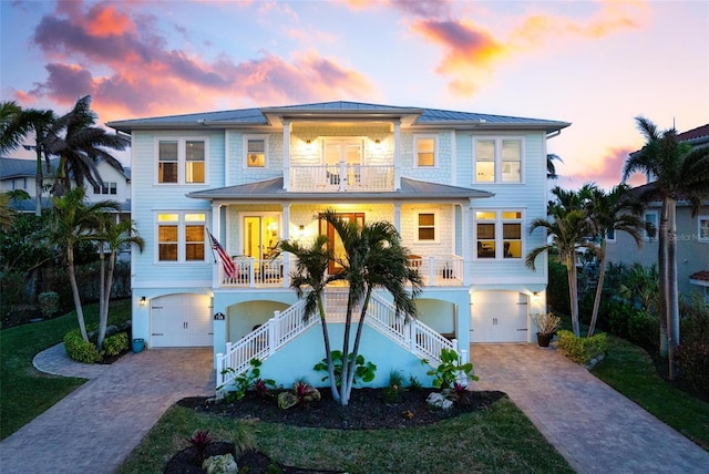 raised beach house with a garage, a balcony, a porch, and stairs