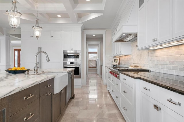 kitchen with custom range hood, decorative backsplash, dark stone countertops, white cabinets, and stainless steel appliances