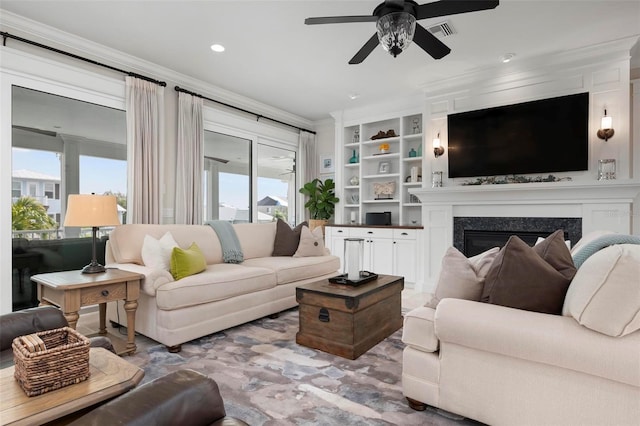 living area with built in shelves, visible vents, a fireplace, ceiling fan, and crown molding