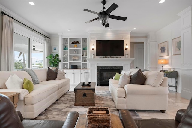 living room with a glass covered fireplace, a decorative wall, built in features, and ornamental molding