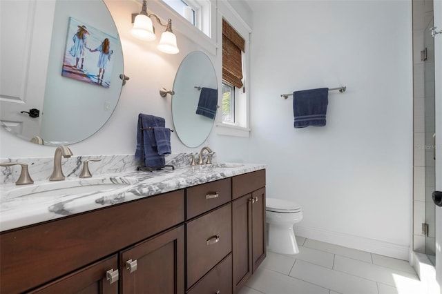 bathroom featuring double vanity, toilet, baseboards, and a sink