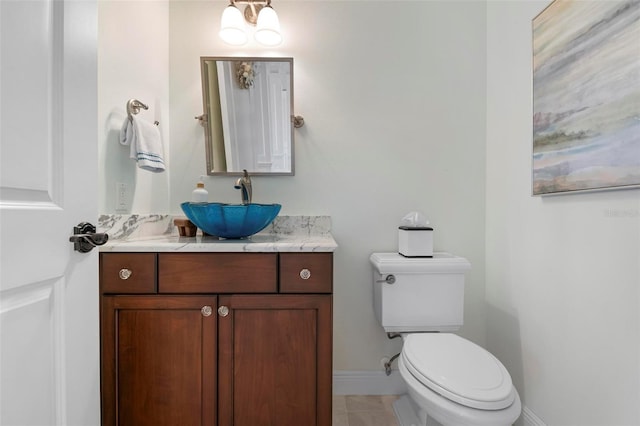 half bathroom featuring tile patterned flooring, toilet, vanity, and baseboards