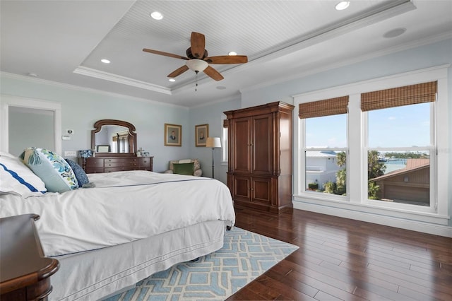 bedroom with recessed lighting, a tray ceiling, dark wood finished floors, and crown molding