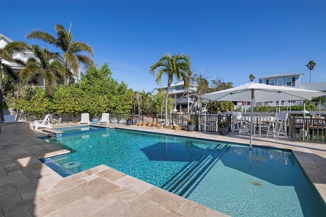 view of pool featuring a patio, fence, and a pool with connected hot tub