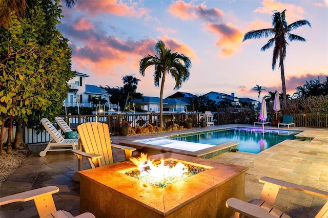 pool at dusk featuring fence, a patio area, a fenced in pool, and a fire pit